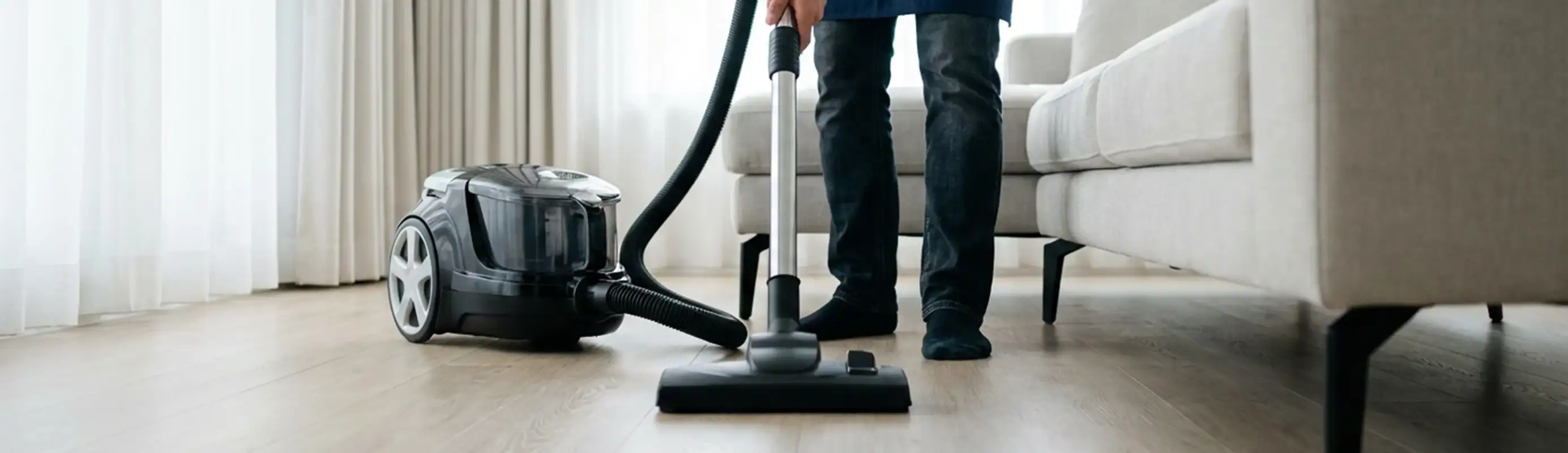 Professional house cleaner vacuuming a living room floor with a canister vacuum cleaner, Allentown, PA.