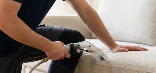 Professional upholstery cleaner deep-cleaning a fabric sofa with a handheld extraction tool, Allentown, PA.